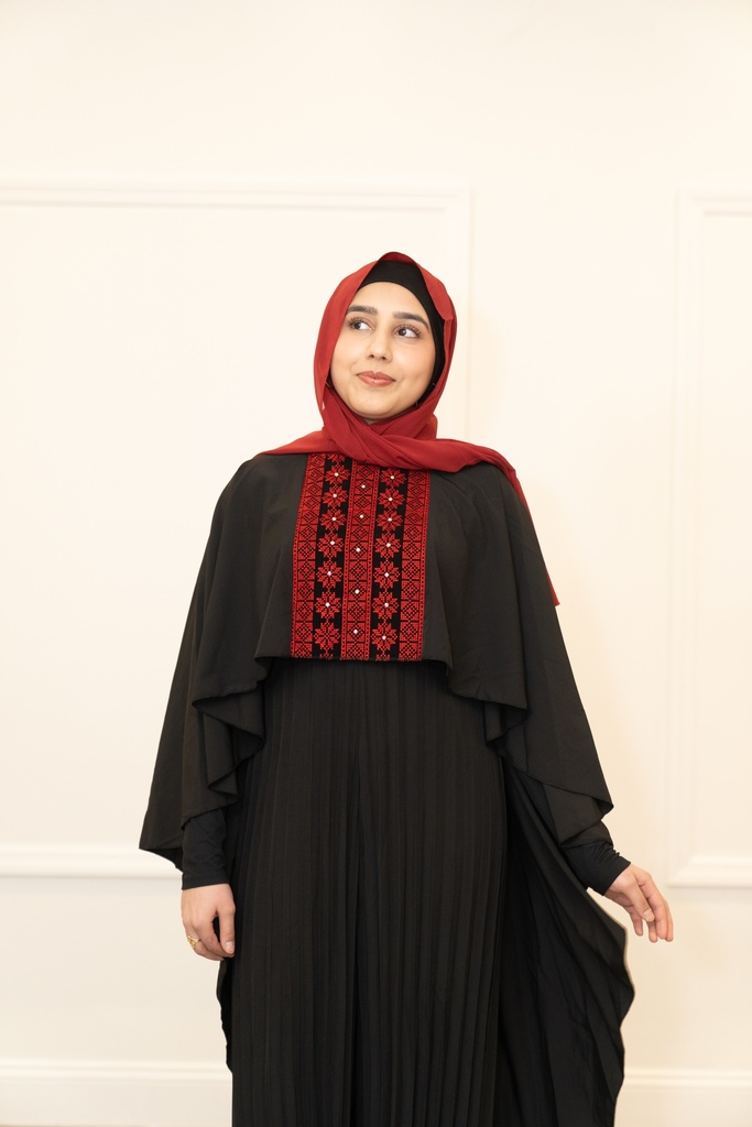This black jumpsuit features wide pleated legs and is handmade in Palestine