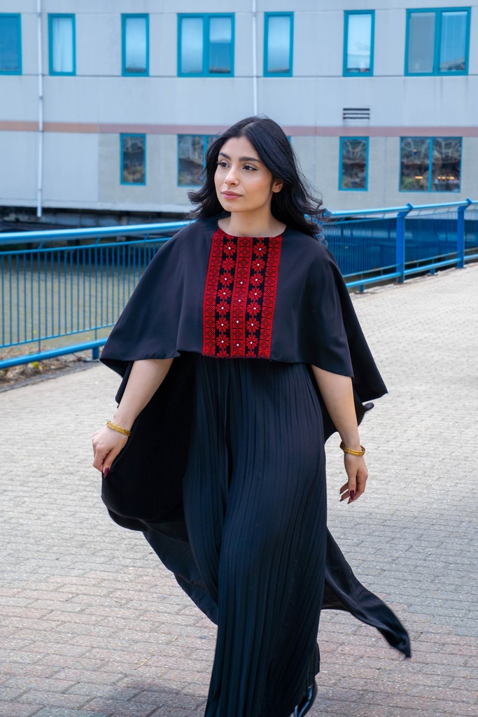 This black jumpsuit features wide pleated legs and is handmade in Palestine